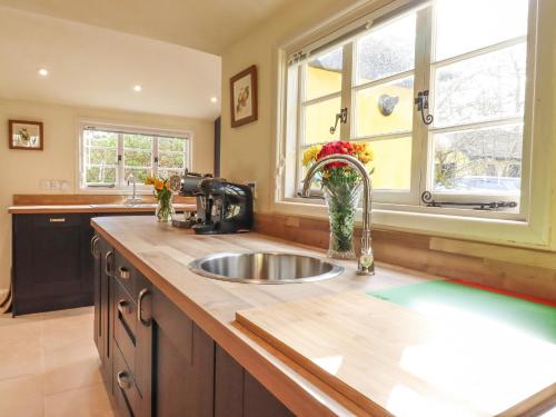 a kitchen with a sink and two windows at The Abbey Cottage in Cockfield