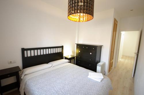 - une chambre avec un grand lit et un lustre dans l'établissement Livingtarifa Apartamento Agaporni, à Tarifa
