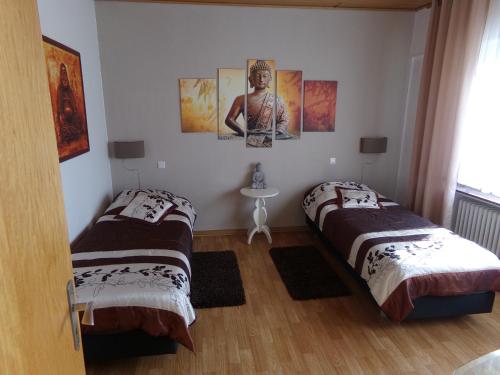 two beds in a room with paintings on the wall at Sauerland-Hotel in Essentho