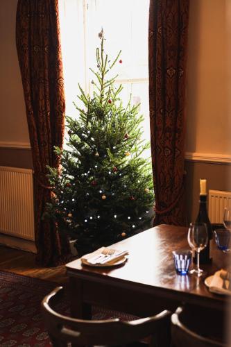 een kerstboom in de hoek van een kamer met een tafel bij The Bruce Arms in Ripon