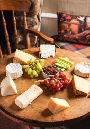 un tavolo in legno ricoperto di formaggio, uva e ortaggi di The Bruce Arms a Ripon