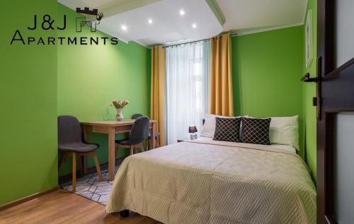 1 dormitorio con paredes verdes, mesa y cama en J&J Apartments, Szczytna 1, Apartament 9, en Toruń