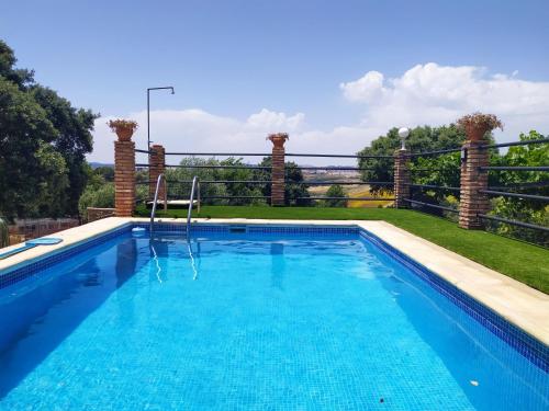 a swimming pool with blue water in a yard at Casa Rural Bellavista Ronda in Ronda