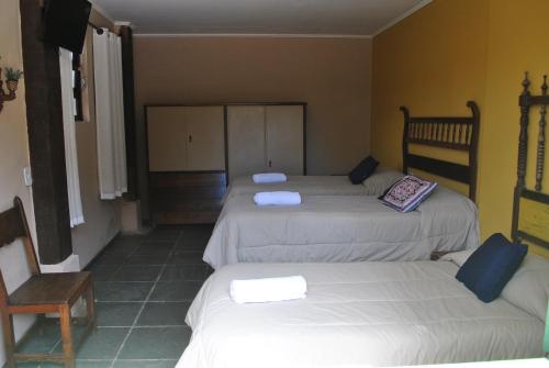 a room with three beds and a chair at Hostel da Montanha in Campos do Jordão