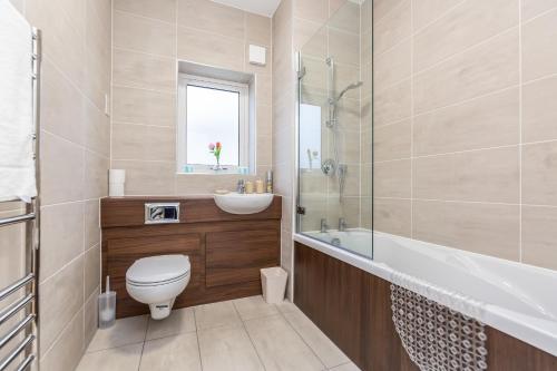 a bathroom with a toilet and a sink and a tub at Lovely 2-Bed Apartment in Dartford in Dartford