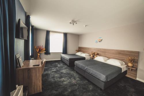 a hotel room with two beds and a desk at Hotel Du Commerce in Oostburg