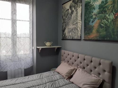 a bed in a bedroom with two pictures on the wall at Le Petit Figuier in Villefranche-du-Périgord