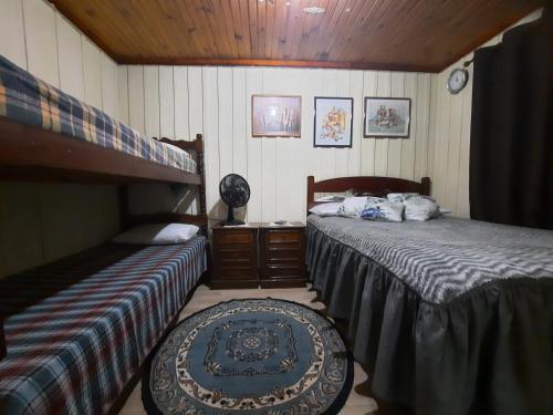 a bedroom with two beds and a table in it at Hospedagem Chalé pousada Chácara Cantinho do Mozão in São Roque