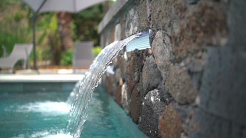 a water fountain coming out of a stone wall at Ô Ruisseau Lodges - Lodge Dattier in Saint-Louis