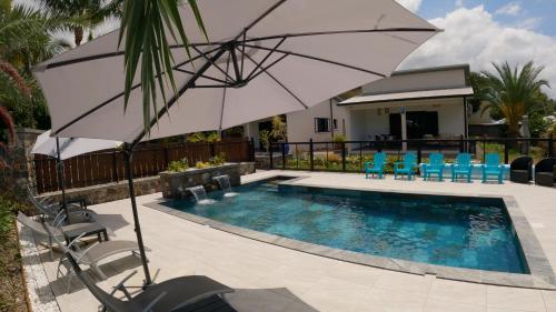 a swimming pool with an umbrella and chairs and a table at Ô Ruisseau Lodges - Lodge Dattier in Saint-Louis