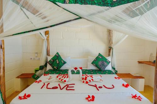 un dormitorio con una cama con amor escrito en ella en Tropicana Garden en Kendwa