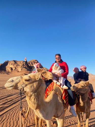 a group of people riding on a camel in the desert at Rum ROZA Luxury Camp in Wadi Rum