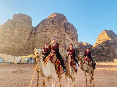a group of people riding on camels in the desert at Rum ROZA Luxury Camp in Wadi Rum