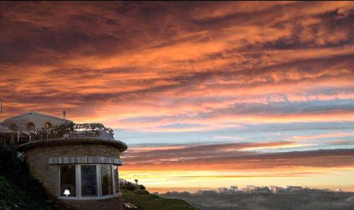 a building on top of a hill with a sunset at VILLA mandala in Ankaran