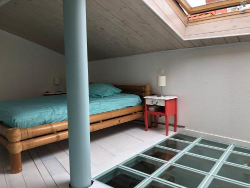 ein Schlafzimmer mit einem Bett und einem Tisch mit einem Fenster in der Unterkunft Maison de pêcheur située dans une impasse privée à 300 m de la mer in Les Sables-dʼOlonne