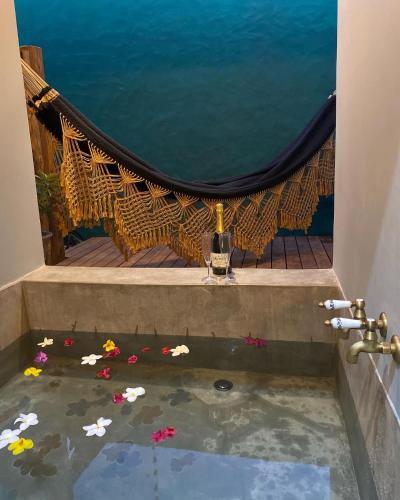 a room with a bathtub with flowers in the water at Tropicália Chalés Boutique in Pipa