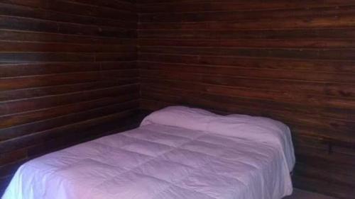 a small bed in a room with wooden walls at CABAÑAS EL CERRO in Ciudad Lujan de Cuyo