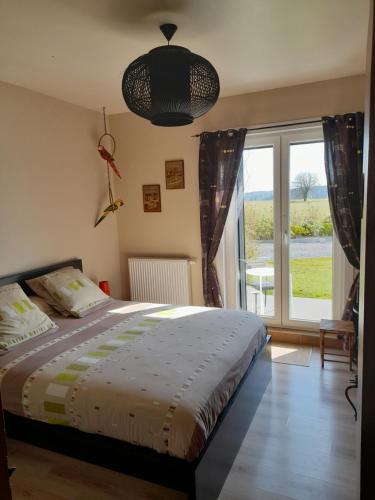 um quarto com uma cama e uma grande janela em B&B Au fil des saisons sur la Wiels em Fauvillers