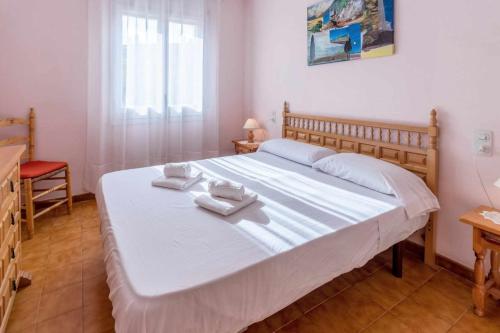 een slaapkamer met een groot wit bed en handdoeken bij Grifeu 17 Apartamento al lado de la playa in Llança