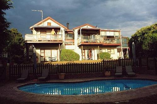 a house behind a fence with a pool in front of it at Swallows Nest Plett in Plettenberg Bay