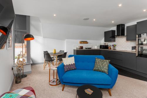 利物浦的住宿－Air Host and Stay - The Scouse House - Quirky 2 bedroom mews house mins from Sefton Park，一间带蓝色沙发的客厅和一间厨房