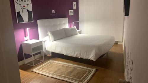 a small bedroom with a white bed and purple walls at Hostal Pozo in León