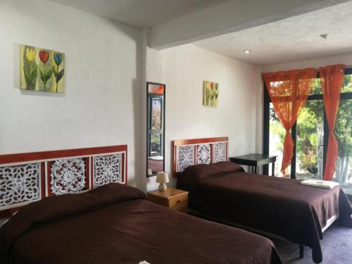 1 dormitorio con 2 camas y ventana en Hotel Porto Bello, en San Pedro La Laguna