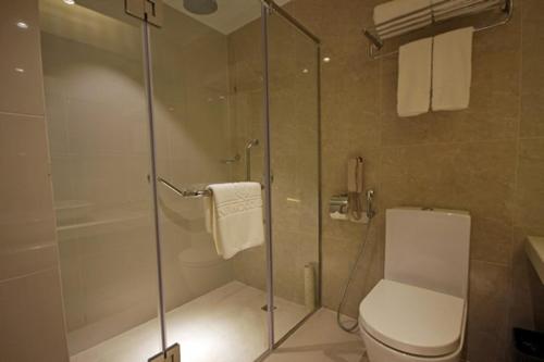 a bathroom with a toilet and a glass shower at Brentwood Suites in Manila
