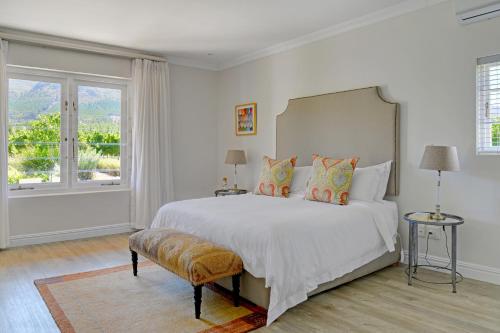 a white bedroom with a large bed and a window at Fransvliet Guest House in Franschhoek