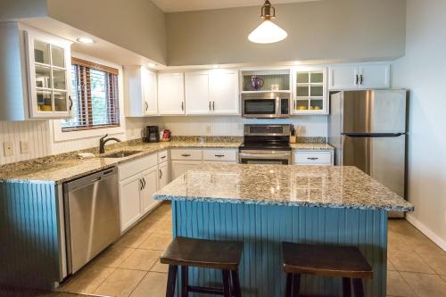 a kitchen with white cabinets and a large island with bar stools at Bay Colony Unit 771 - Upper Level in Nisswa