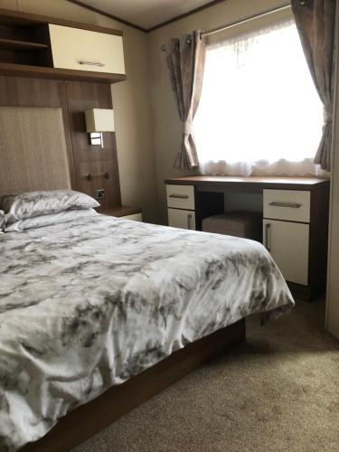 a bedroom with a bed and a desk and a window at River View in Dunoon