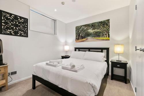 a bedroom with a bed with two towels on it at Urban City Escape with pool, gym, sauna and spa in Auckland