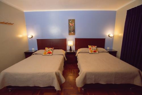 2 camas en una habitación con paredes azules en Hospedaje Zaragoza, en Ayacucho