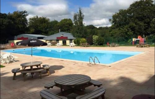 a swimming pool with a picnic table and an umbrella at Whiskey river chalet-Glan Gwna Holiday Park in Caernarfon