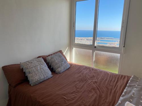 1 cama con 2 almohadas en una habitación con ventana en Apartamento 24th floor & sea view, en Alicante