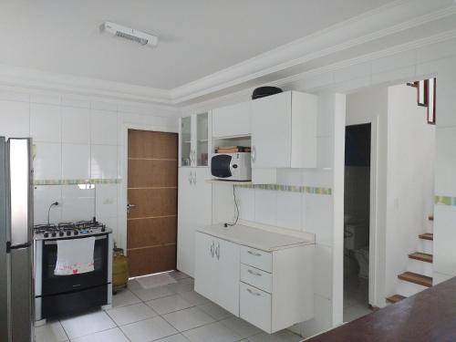 a kitchen with white cabinets and a stove at Linda Casa, 3 quartos, acomoda 10 pessoas, há 1,5 km da praia da Enseada in Guarujá