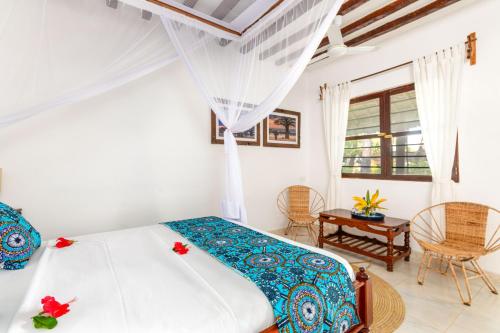 a bedroom with a bed and a table and chairs at Poa Poa Bungalows in Kiwengwa