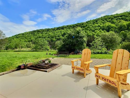 two wooden chairs sitting on a patio in front of a field at The Maples Apt - King Bed, Pet Friendly, Beautiful Views in Ellicottville