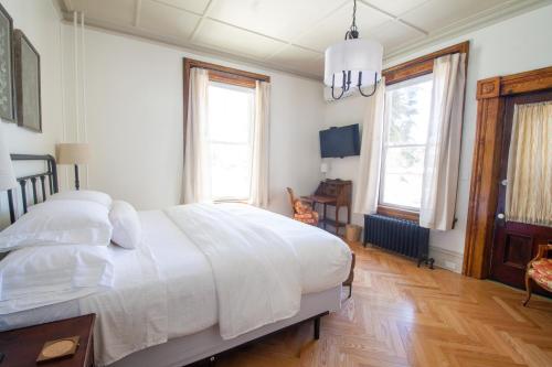 a bedroom with a large white bed and windows at Pert House in Potsdam