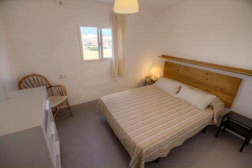 a bedroom with a bed with a wooden headboard and a window at Vivienda Rural Cortijo de Liche in Arcos de la Frontera