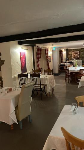 un comedor con mesas y sillas blancas y una registradora blanca en Prestleigh inn, en Shepton Mallet