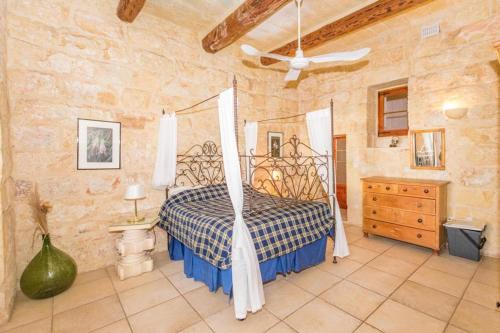 a bedroom with a bed in a stone wall at Farmhouse Cala2 in Qala