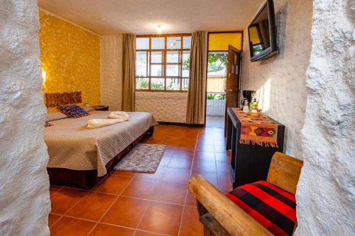 a bedroom with a bed and a television and a chair at Hotel Fonda del Sol in Panajachel