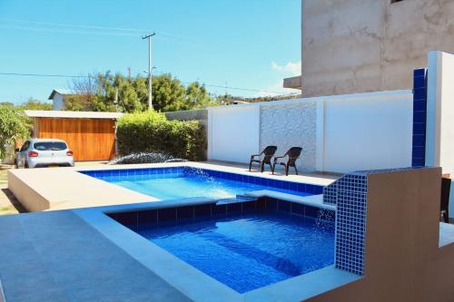 a swimming pool with two chairs next to a house at Cabaña Villas de Santa Veronica in Juan de Acosta