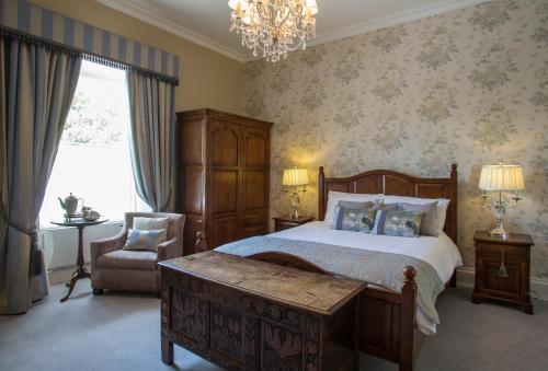 a bedroom with a bed and a chair and a chandelier at Raheen House Hotel in Clonmel
