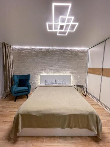 a bedroom with a bed and a blue chair at Park & Beach Area Apartment in Liepāja