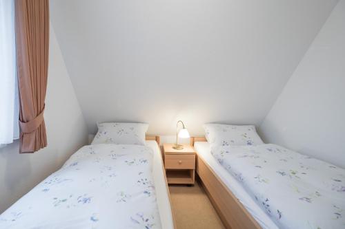 two twin beds in a room with a night stand at Direkt am Deich - Ferienwohnung Oland im Gästehaus Am Badedeich in Dagebüll