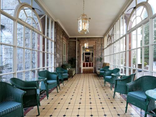 a restaurant with green chairs and tables and windows at Macdonald Leeming House in Watermillock
