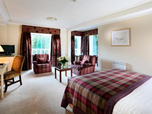 a hotel room with a bed and a desk and chairs at Macdonald Leeming House in Watermillock