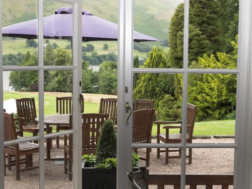 an open door with a table with an umbrella at Macdonald Leeming House in Watermillock